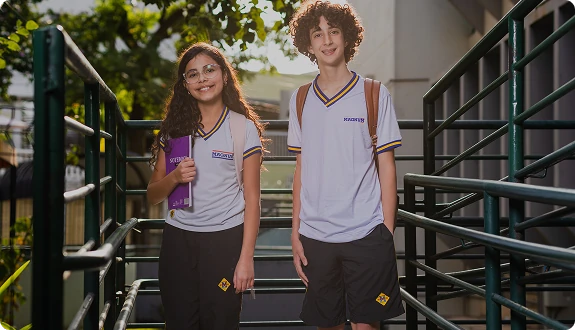 Dois alunos do Colégio Magnum descendo a escada da escola, com caderno e mochila