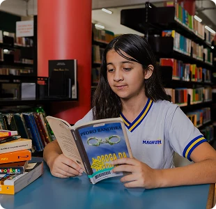 Aluna do Colégio Magnum lendo um livro na biblioteca