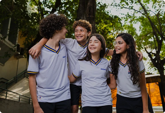 Grupo de quatro alunos do Colégio Magnum sorrindo juntos na área externa da escola