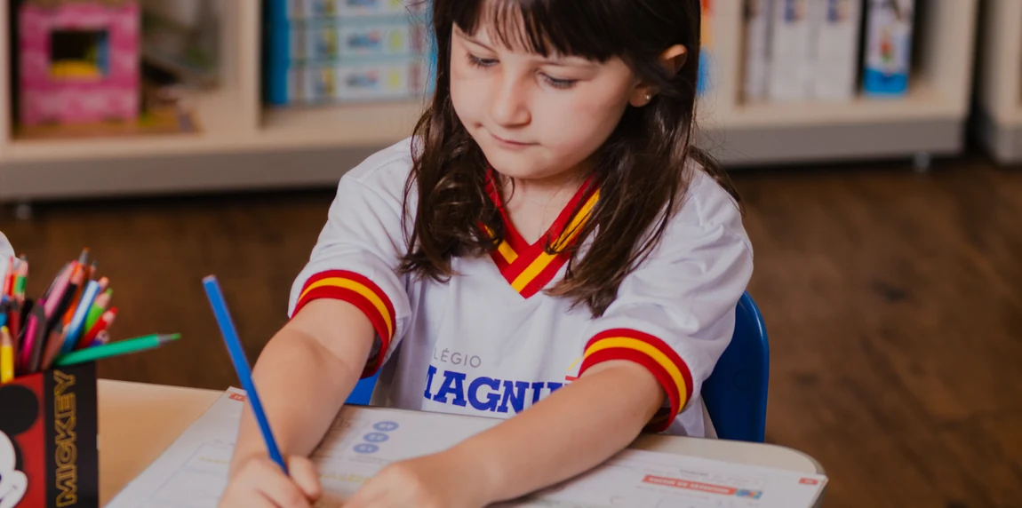 Menina do Colégio Magnum desenhando com lápis de cor na sala de aula